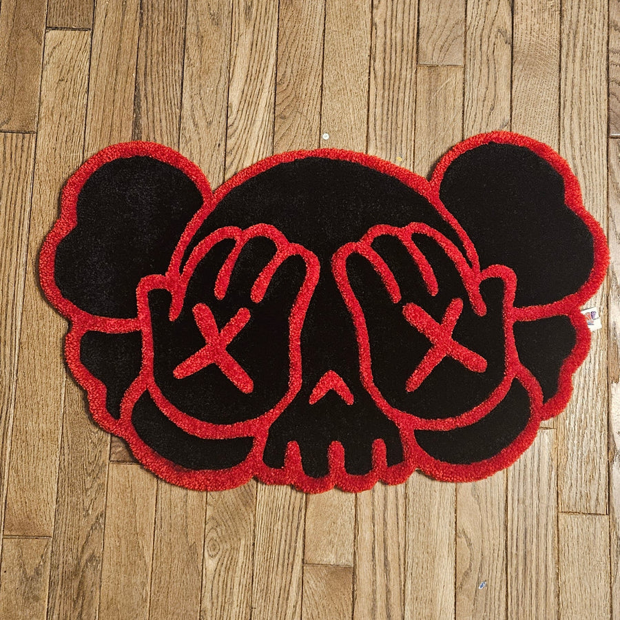 Black and red decorative mat with hand designs on a wooden floor